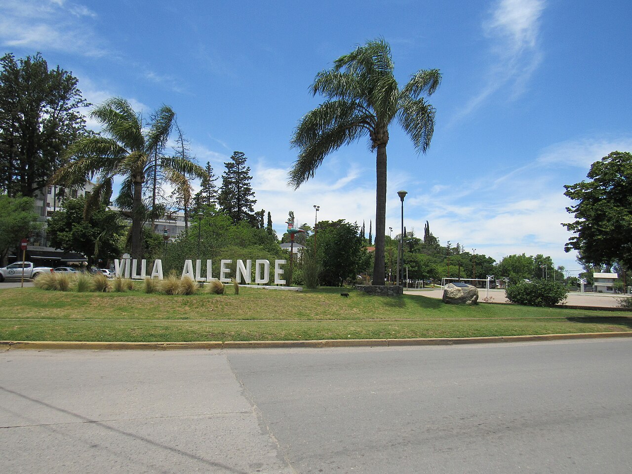 El cartel de Villa Allende junto a las palmeras de la avenida de entrada